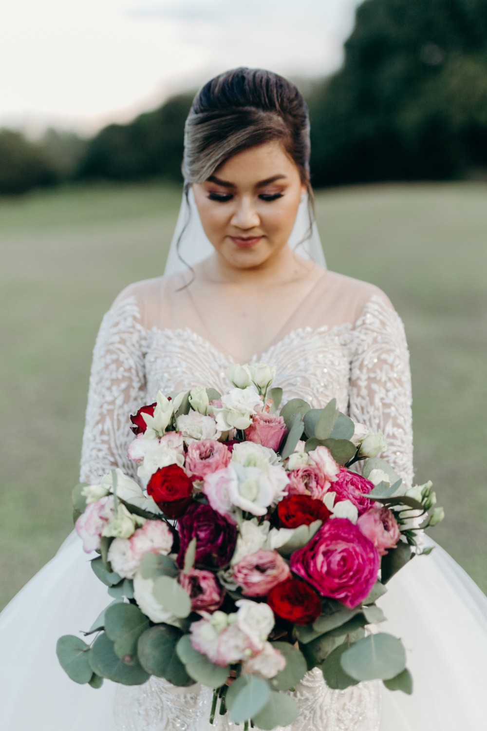 Bride in a long-sleeved embellished gown and groom in a burgundy tuxedo walking down the aisle